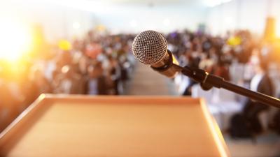 A microphone at a podium overlooking an audience out of focus in the background