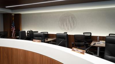 Chairs behind a desk with a large logo of the FEC on the wall behind them