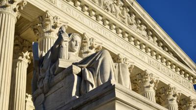 A statue in front of the columns of the Supreme Court building