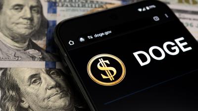The DOGE logo on a smartphone screen on top of $100 bills