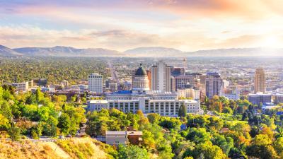 A view of the buildings in Salt Lake City with the mountains and sun behind them