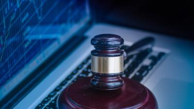 Judges gavel on laptop keyboard with stock graphs on screen