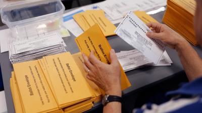 A person's hands removing ballots from envelopes