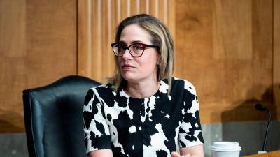 Kyrsten Sinema sitting at a desk looking sideways at the camera