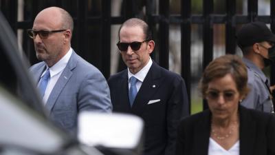 A man in a suit wearing sunglasses with other people around him also wearing sunglasses
