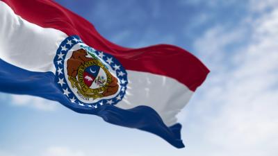 State flag of Missouri waving against a blue sky with white clouds