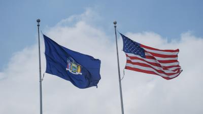 The New York State flag flying next to an American flag.