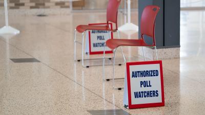 Two empty chairs and two signs that say "Authorized Poll Watchers".
