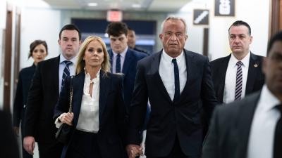 Robert F. Kennedy Jr. and Cheryl Hines walking down a hallway with a group of people