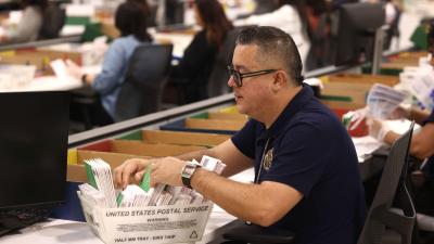 A man sorts through a box of ballots