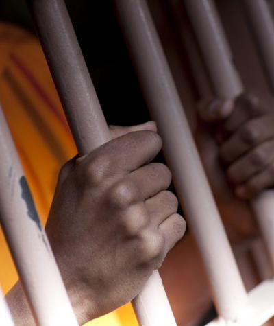 Stock photo of person behind prison bars