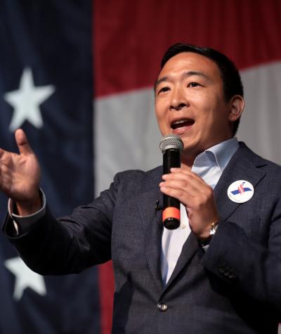 Andrew Yang speaking in front of an American flag
