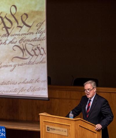 Trevor Potter on stage with an image of the U.S. Constitution behind him.