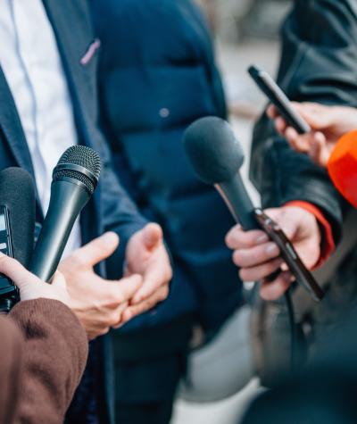 Microphones pointed towards a man in a suit.