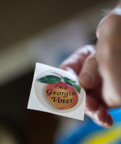 Hand holding sticker that says I'm a Georgia Voter