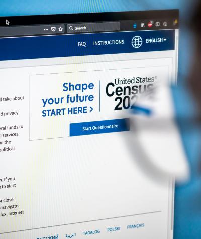 Online census form with out of focus person wearing glasses looking at screen 