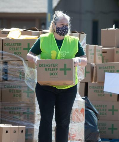 A woman wearing a homemade coronavirus mask carries a box that has "Disaster Relief" printed on it