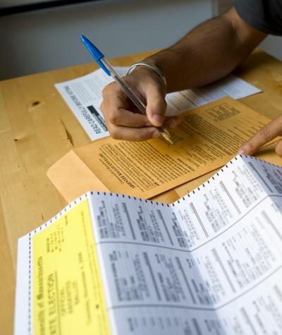 Shot of a person's hands at a table filling out an absentee ballot