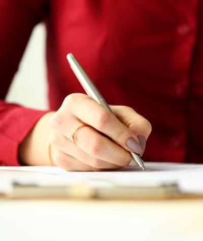 A woman in a red shirt writing on a piece of paper