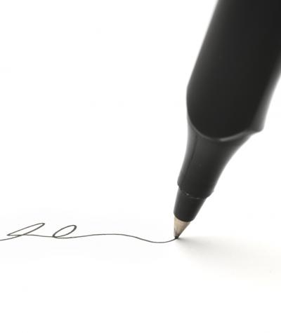 Close up of a pen signing a piece of paper