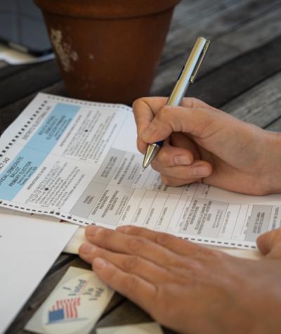 Close up of a person's hand filling out an absentee ballot