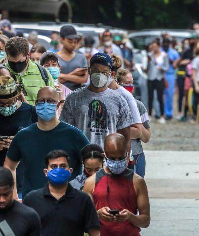 A long line of people in face masks waiting to vote