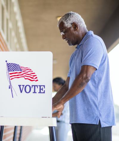 A black man votes at a voting booth