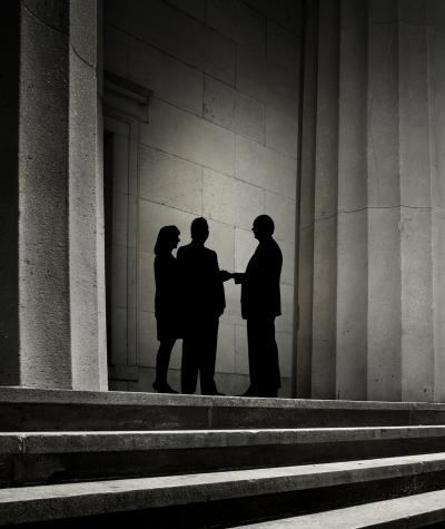 Silhouettes of three figures meeting among a group of columns