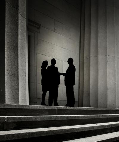 Silhouettes of three figures meeting among a group of columns