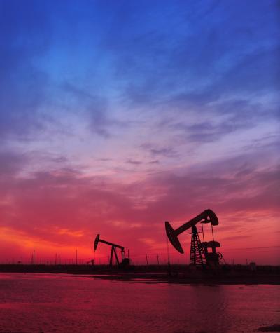 Silhouettes of oil pumps against a sunset