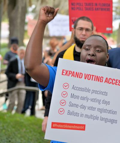 A group of people holding signs that say "Expand Voting Access in Florida".