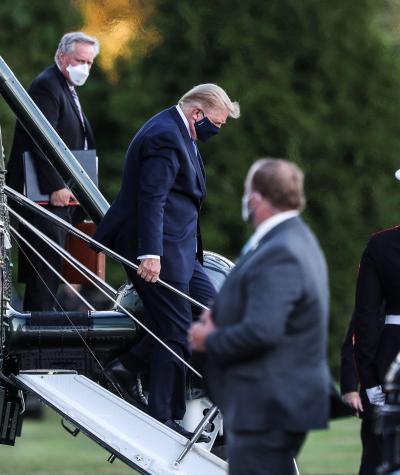 Donald Trump wearing a mask while descending the steps of a helicopter