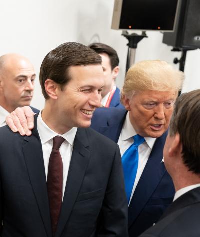 Donald Trump with his arm over Kared Kushner's standing among a group of people