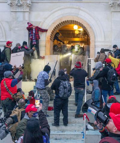 People crowd around an arch doorway while police defend the building