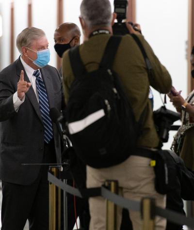 Lindsey Graham wearing a mask and speaking to a group of reporters