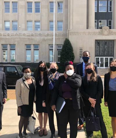 A group of people wearing masks standing in front of a courthouse.