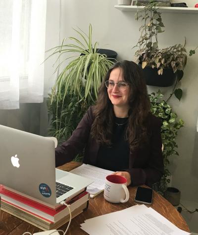 Danielle Lang sitting at a desk in front of a laptop with a lot of plants behind her