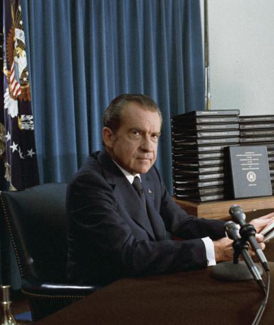 Nixon sitting at a desk in front of a microphone