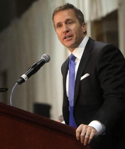Eric Greitens speaking into a microphone at a podium.