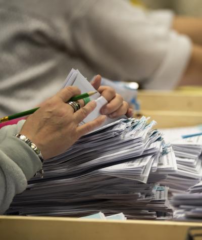 A woman's hands counting a stack of ballots.