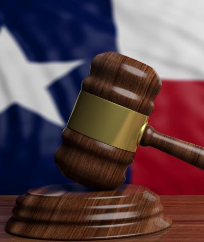 A gavel in front of the state flag of Texas