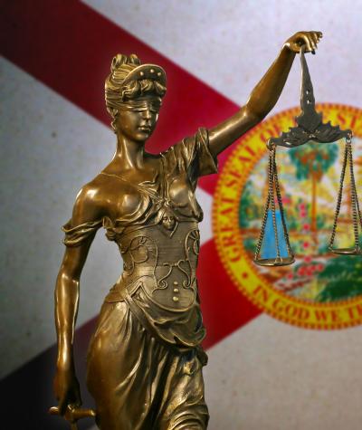 A statue of lady justice in front of the state flag of Florida.