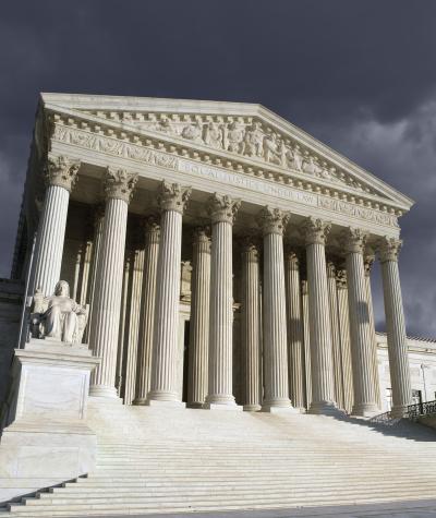The front of the Supreme Court building with a stormy sky behind it