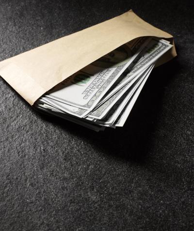$100 bills in an envelope on a dark background
