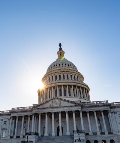 The dome of the U.S. Capitol Building with a sunburst appearing behind it.