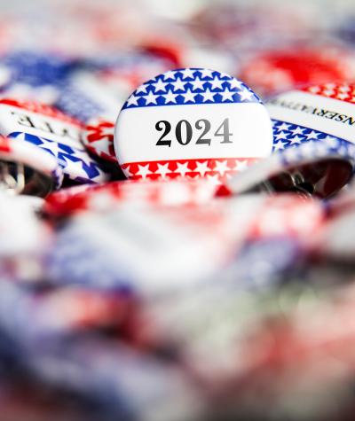A pile of buttons with stars and stripes on them. One button in focus says "2024"