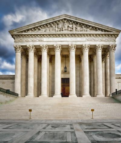 Front of the U.S. Supreme Court building under a dramatic sky with clouds