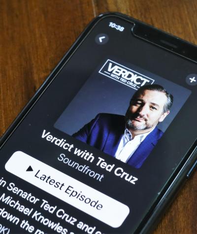 A smartphone on a desk with an image of Ted Cruz's podcast "Verdict with Ted Cruz" on the screen
