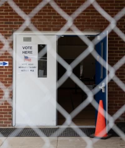 The open door of a polling place seen through a chain link fence.