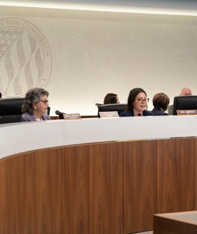 FEC commissioners Shana Broussard, Ellen Weintraub and Dara Lindenbaum seated at a long curved table during a hearing.